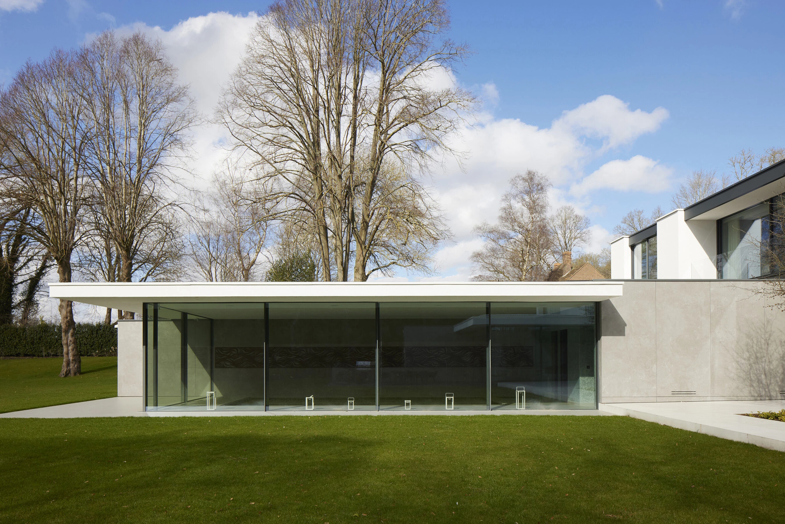 Contemporary house in Radlett with broad sliding glass doors opening towards the lawn