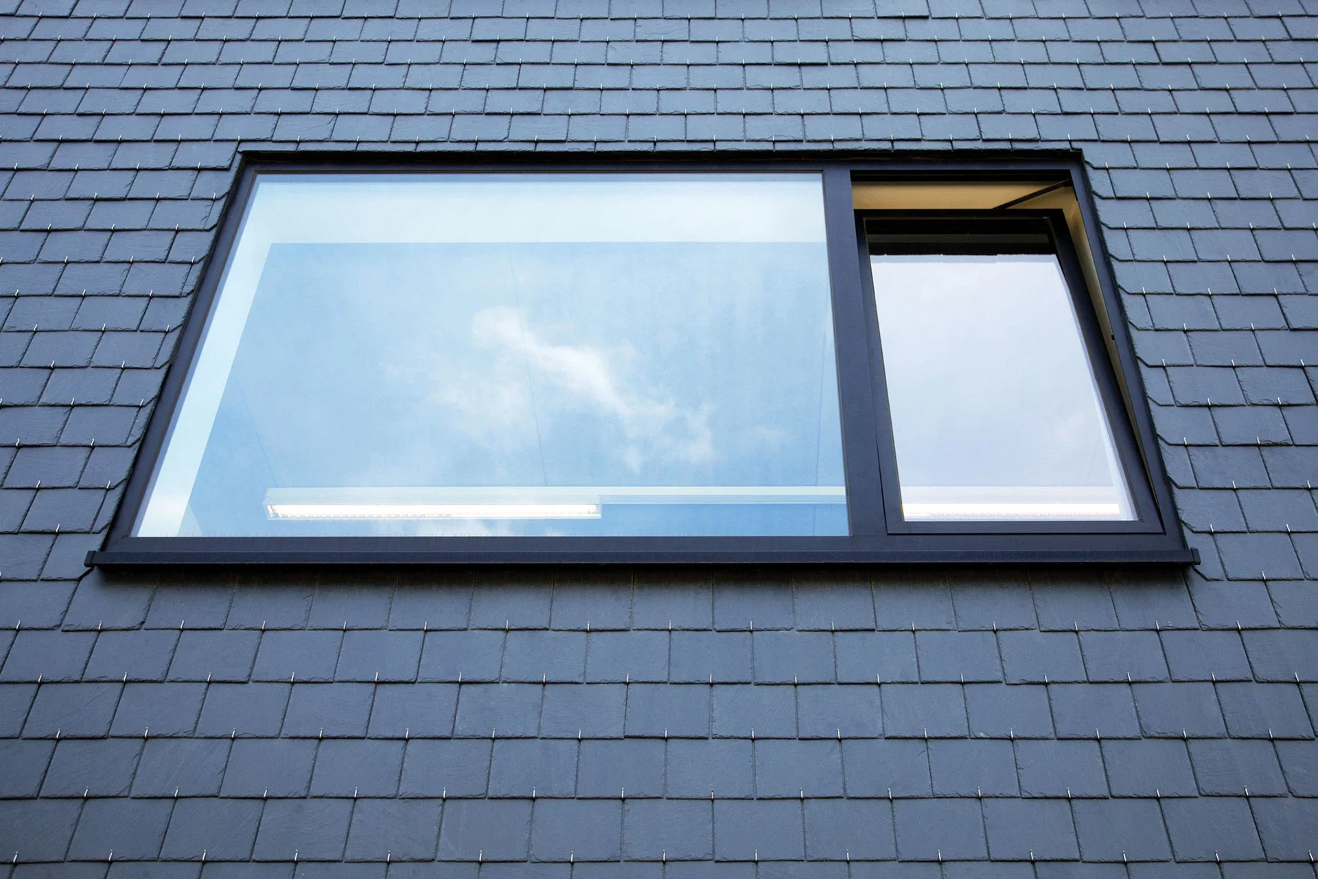 Aluminium tilt-and-turn window in a slate-clad wall