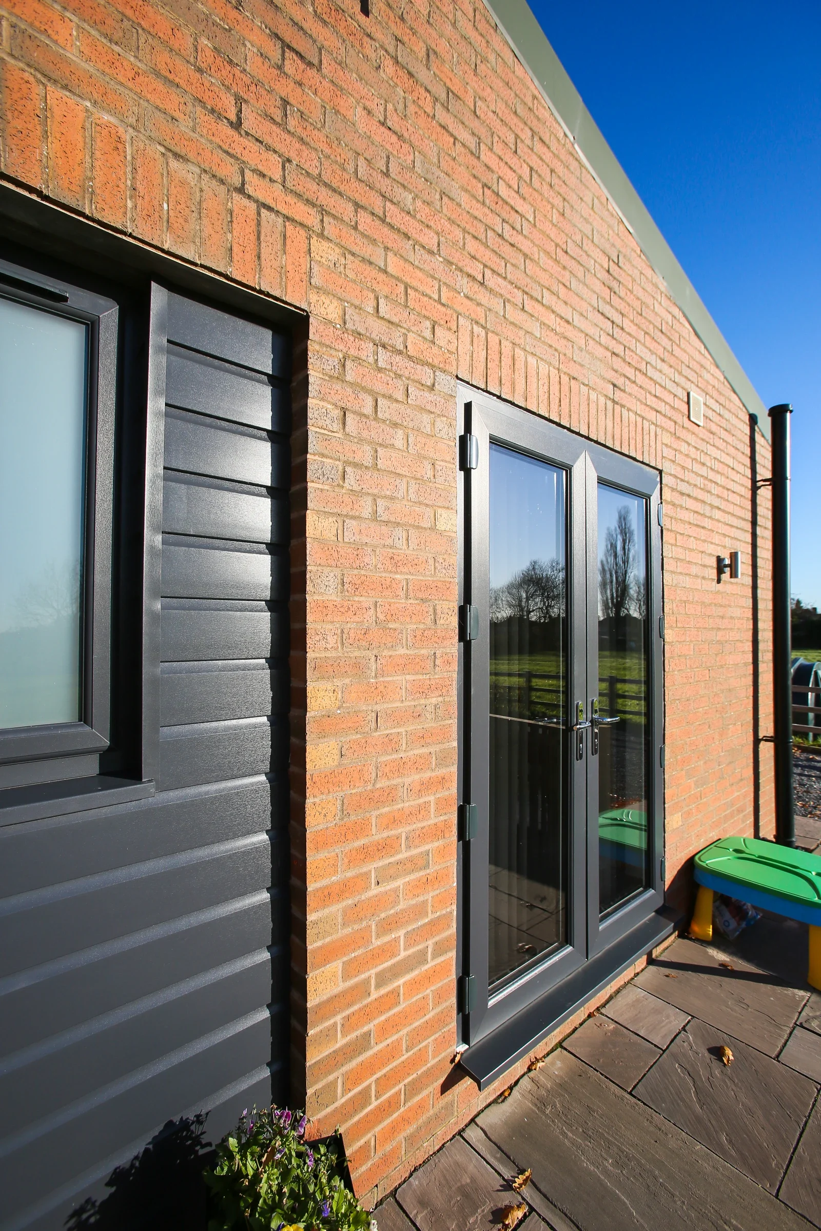 Black uPVC French doors in a brick and timber-clad home