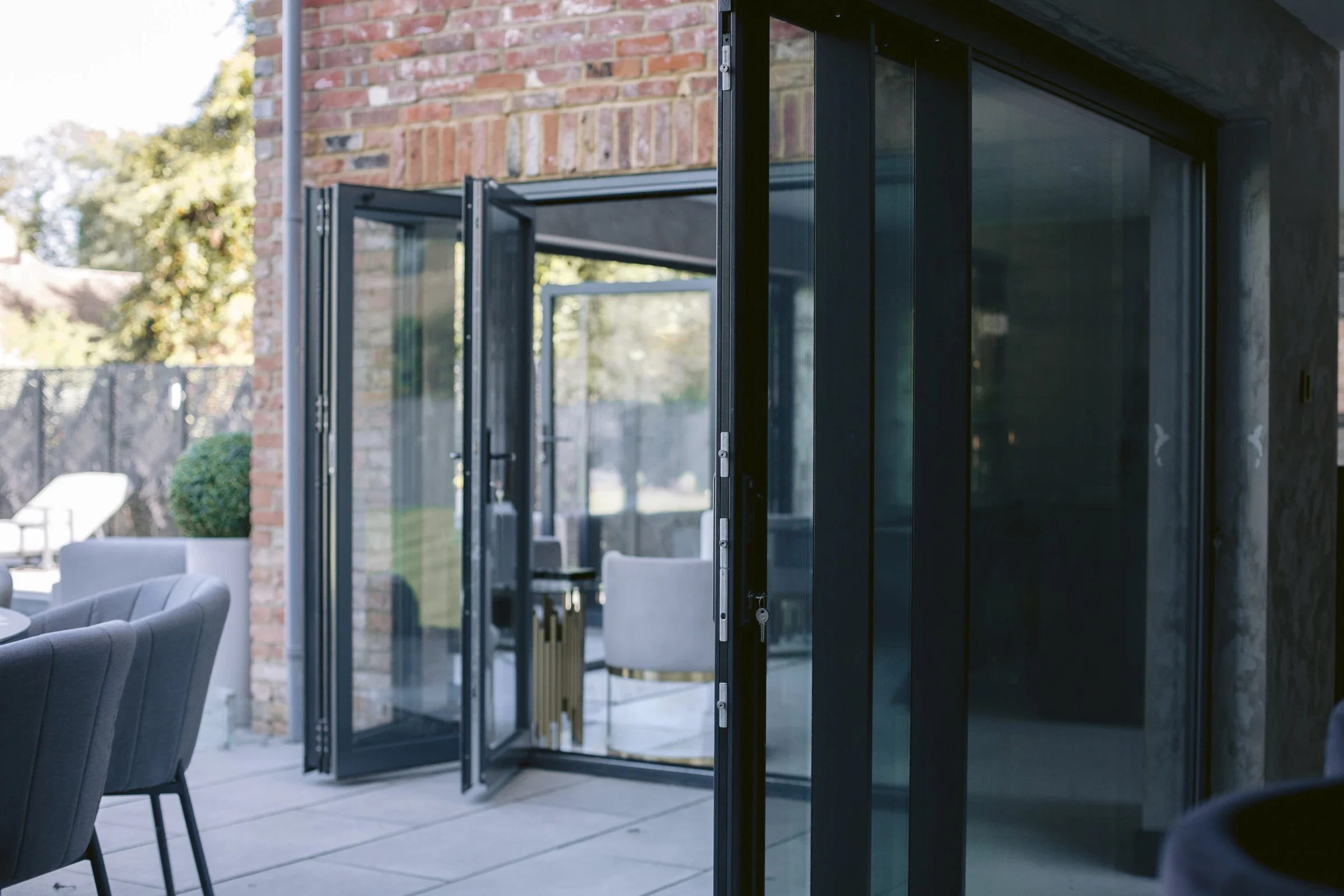 Modern glass aluminium bi-folding and sliding doors opening to an outdoor patio