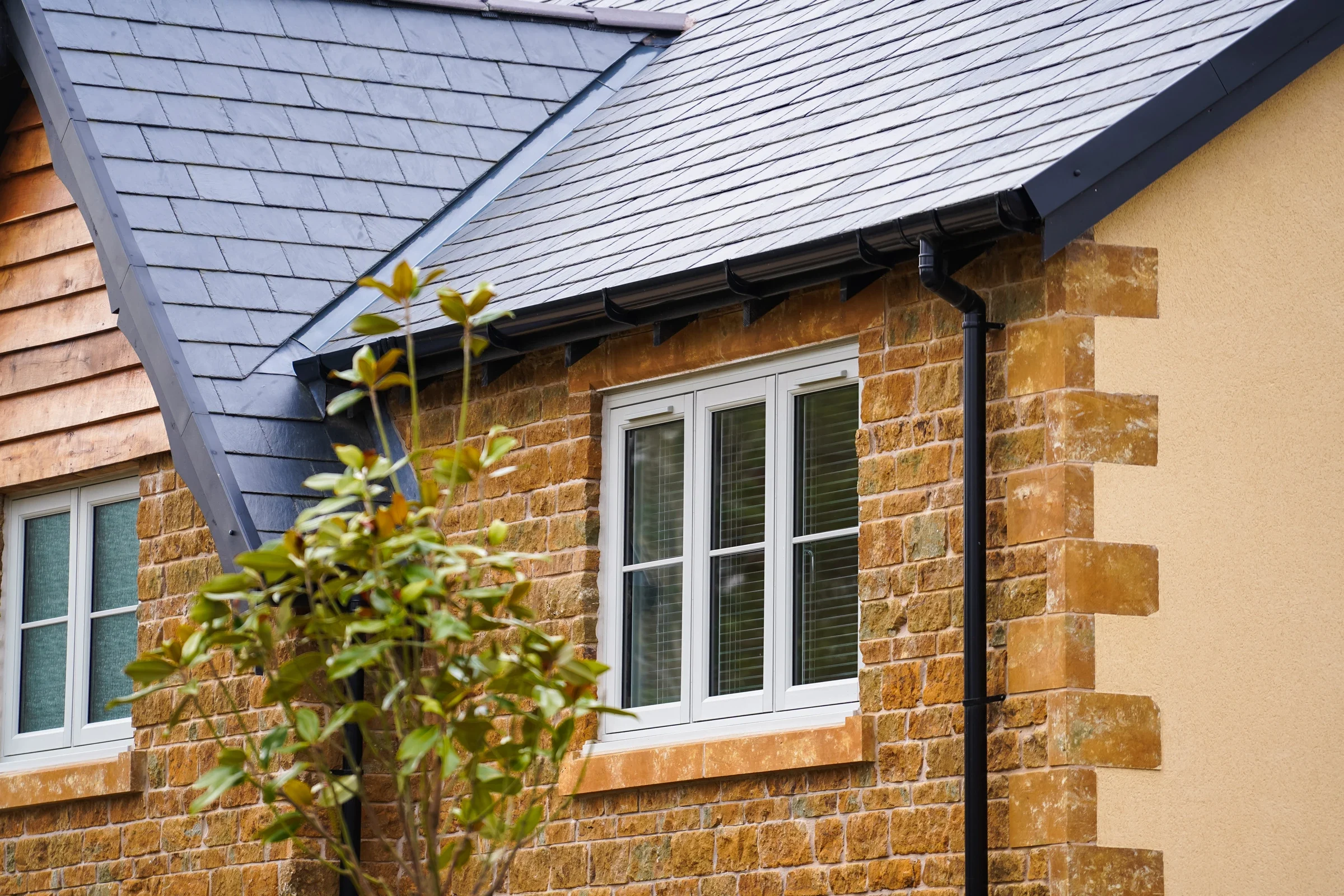 Agate grey flush uPVC windows in a stone and timber-clad house