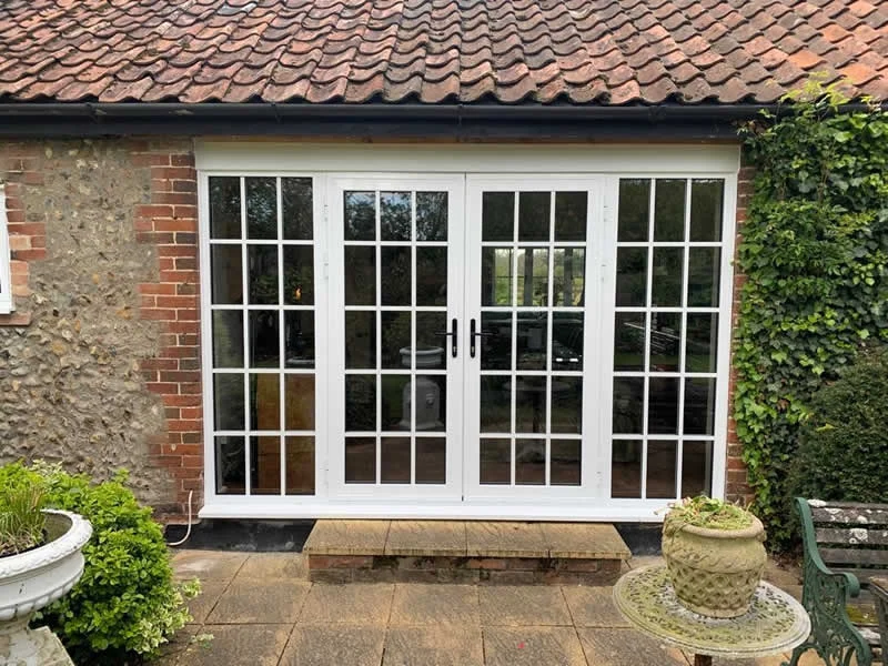 White aluminium French doors and sidelights in a brick and flint house