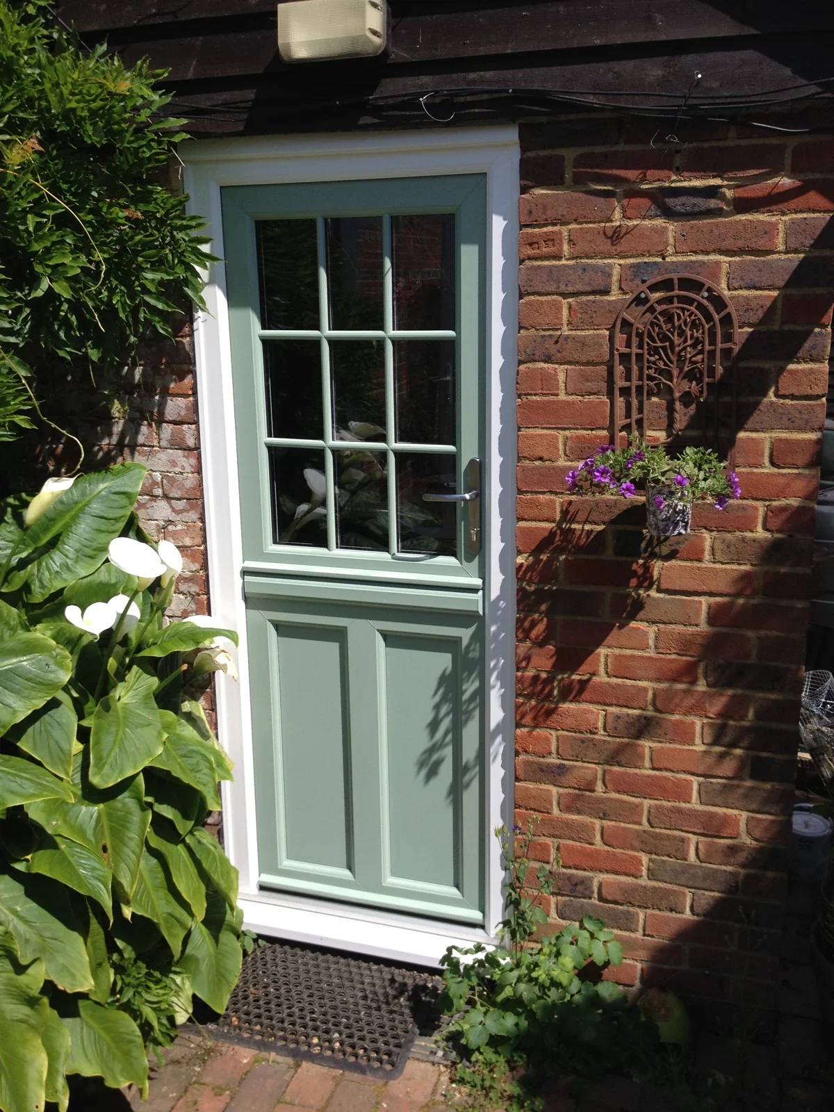 Green uPVC stable door in a traditional brick cottage entrance