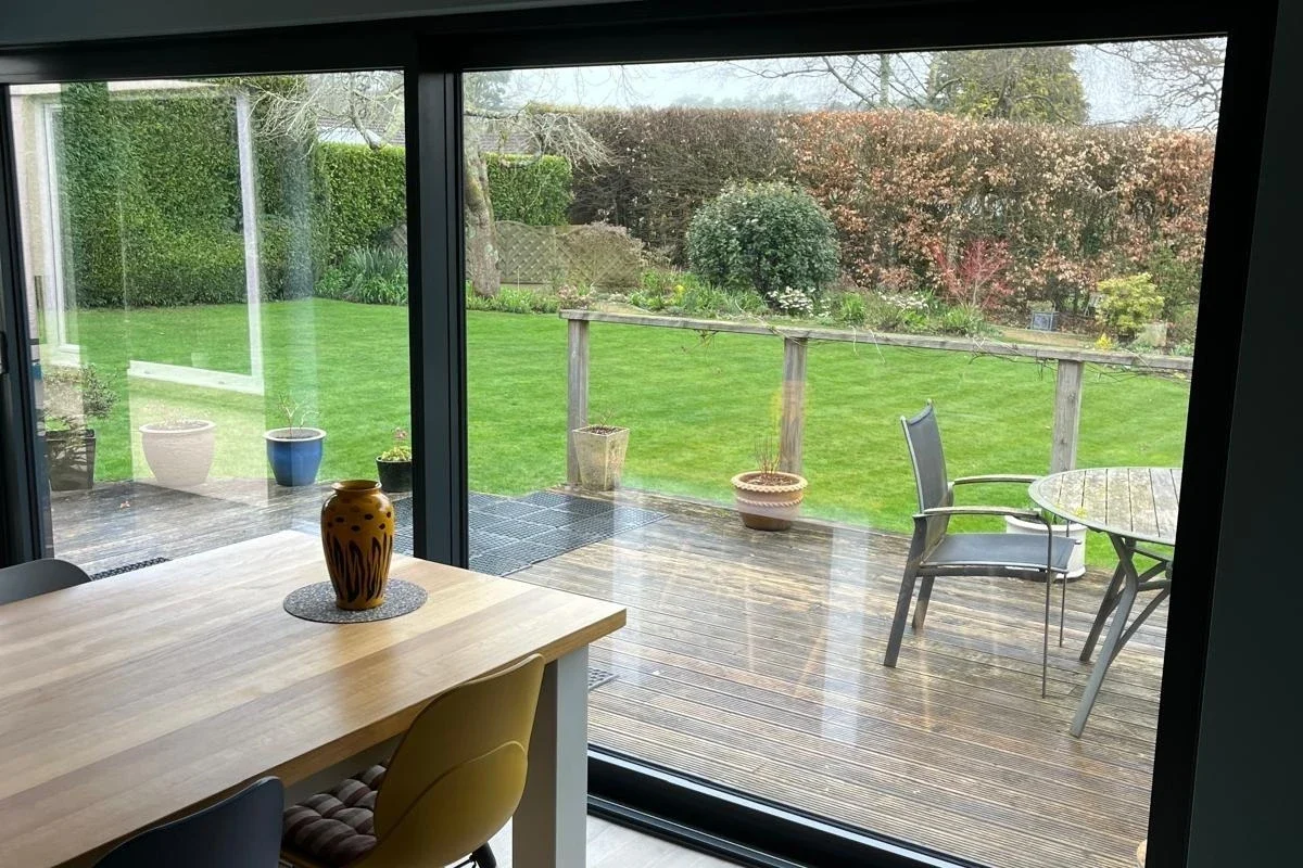 Open lift-and-slide doors overlooking a garden dining terrace