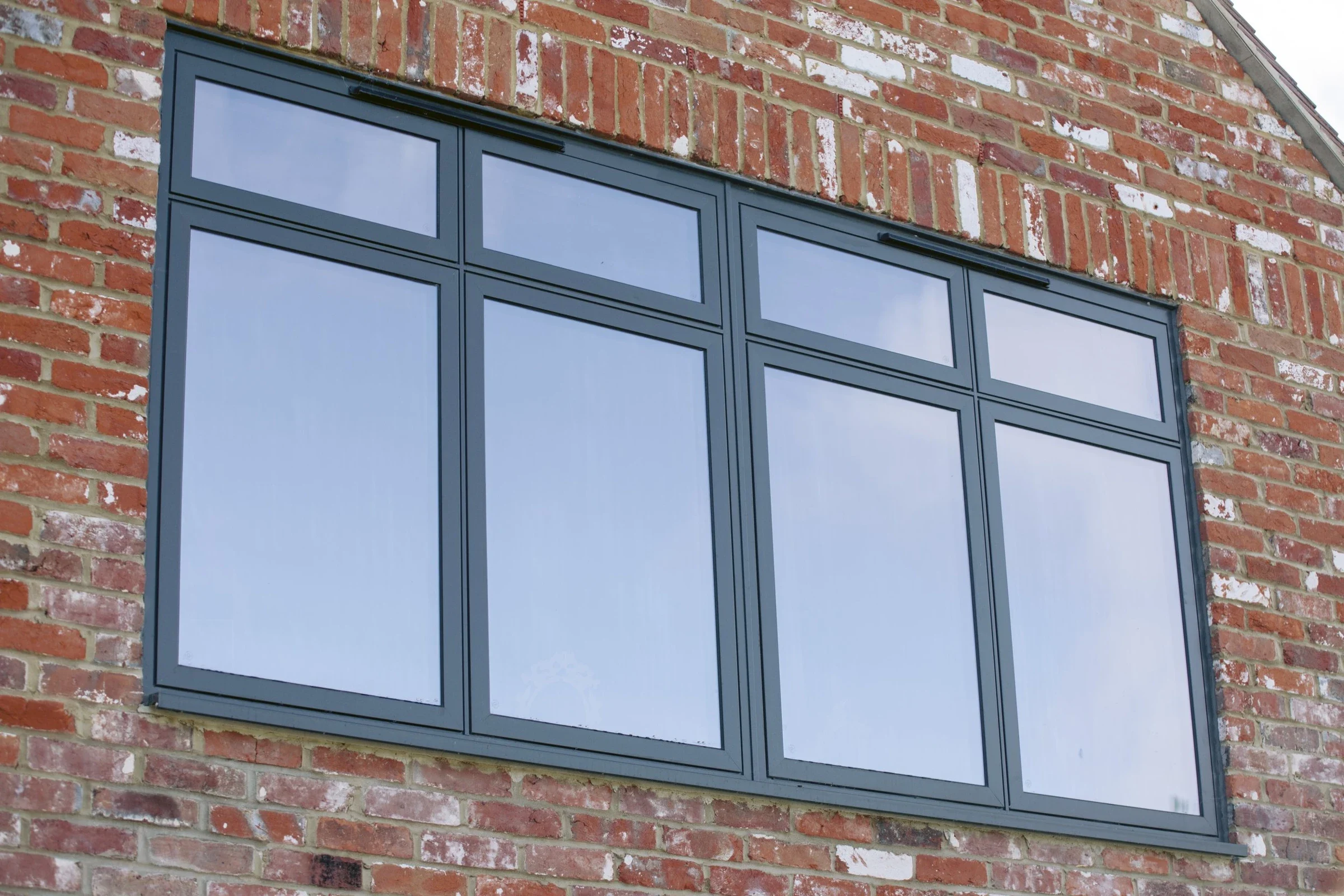 Modern aluminium anthracite grey-framed windows on a brick building exterior
