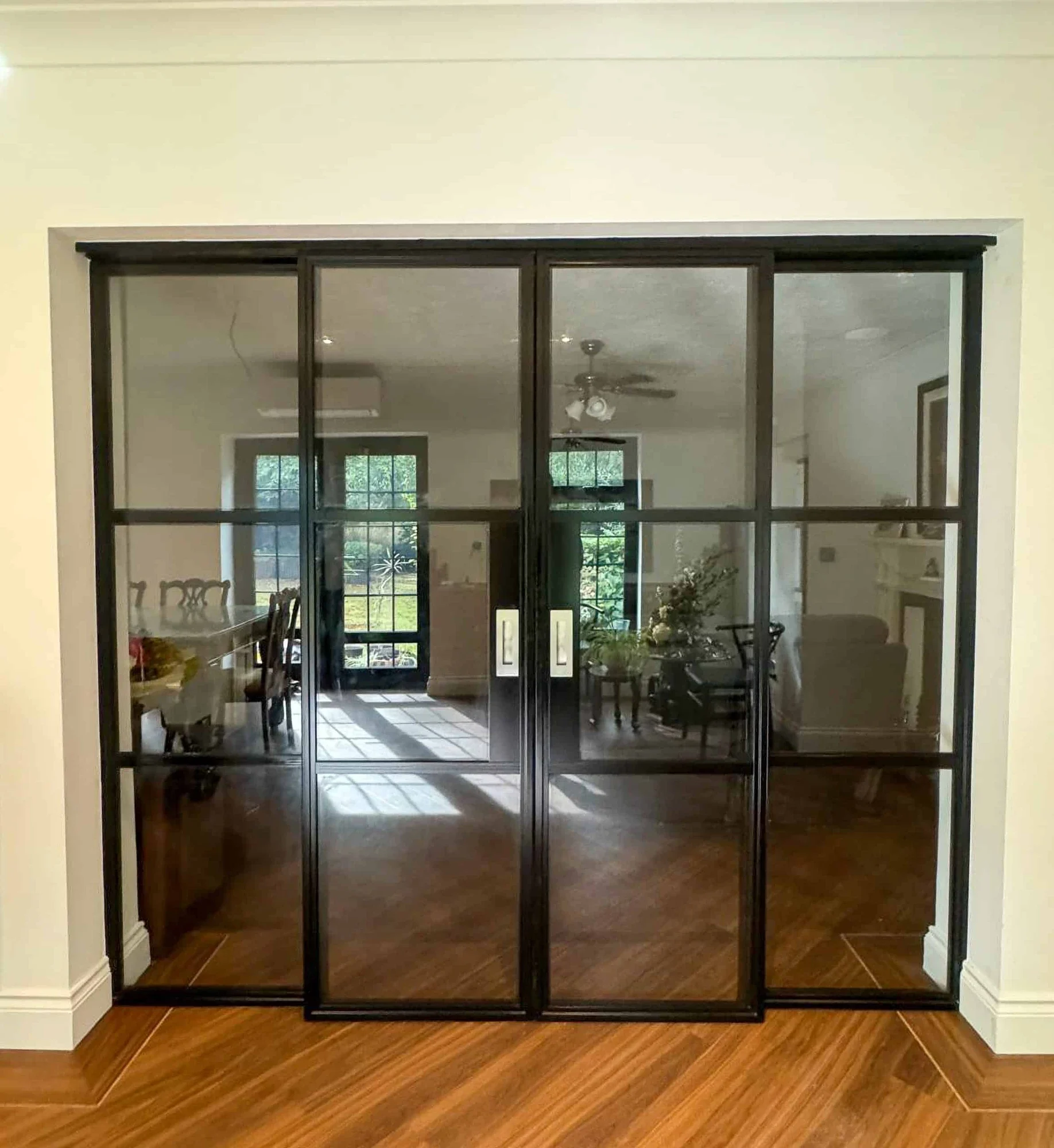 Black internal aluminium sliding doors dividing two furnished living spaces