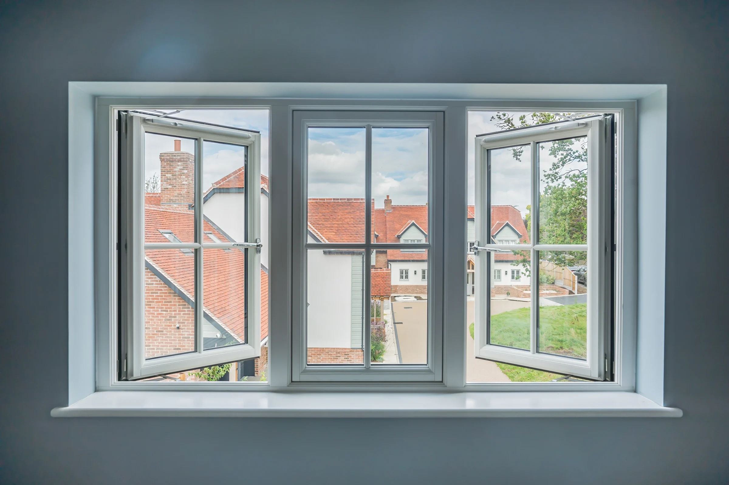 White uPVC flush casement windows open above a garden