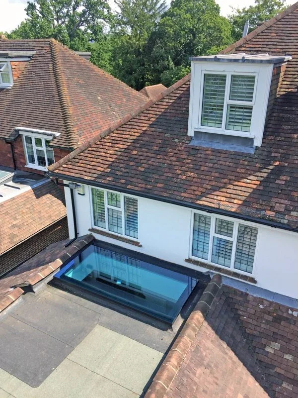 Flat glass rooflight viewed from above a house extension