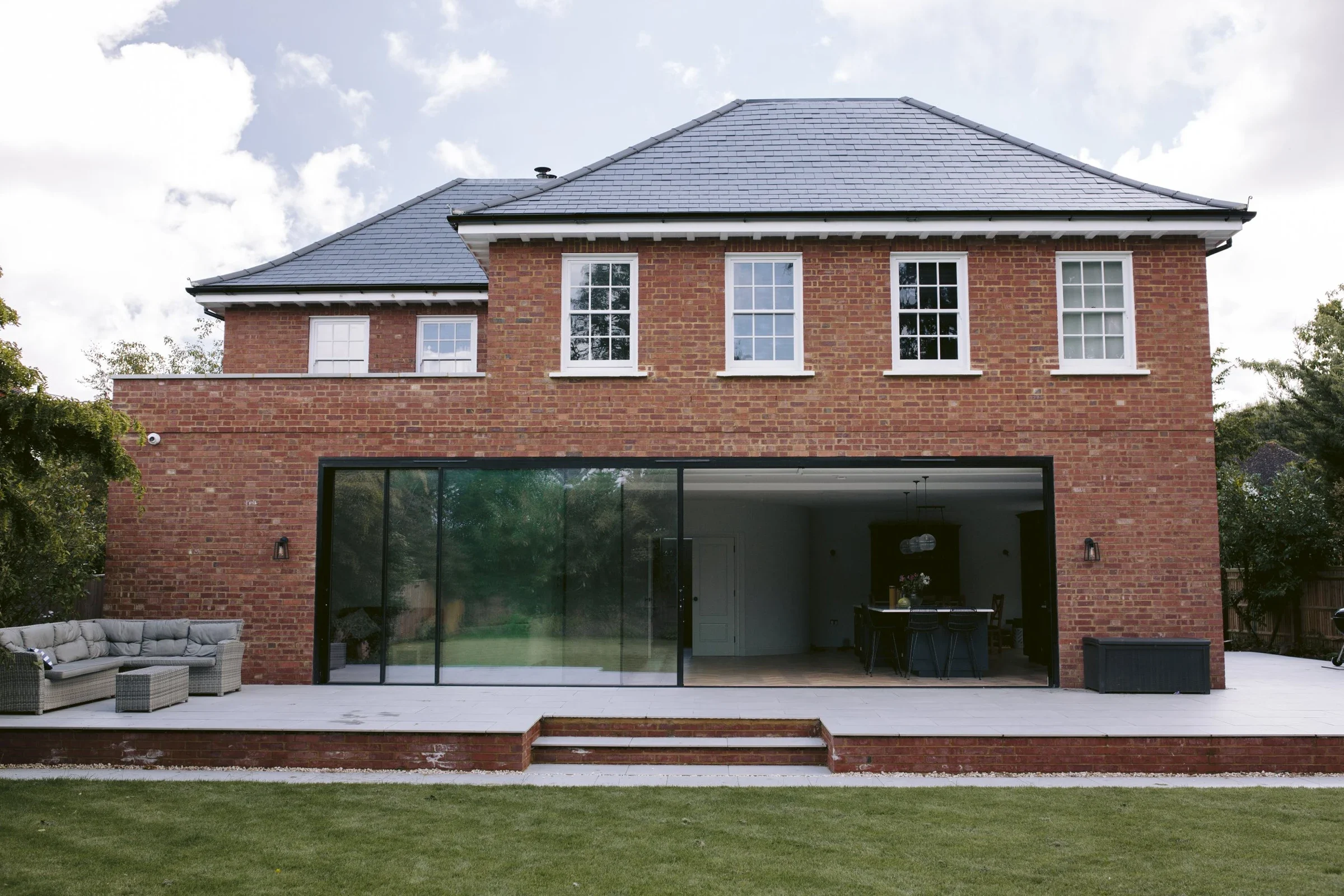 Modern brick house with large aluminium glass sliding doors, and white timber windows