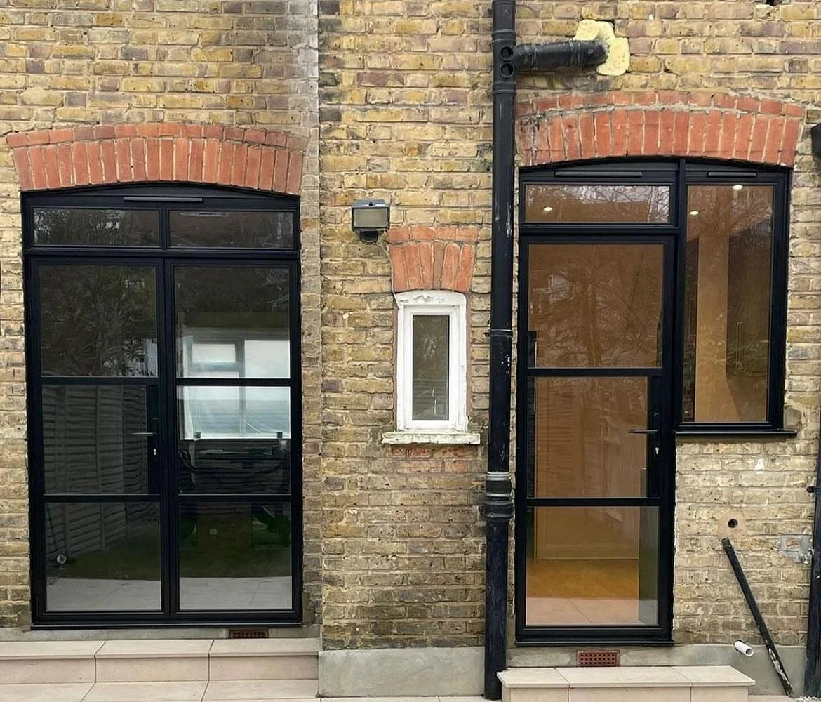 Black heritage single door and sidelight alongside matching garden doors