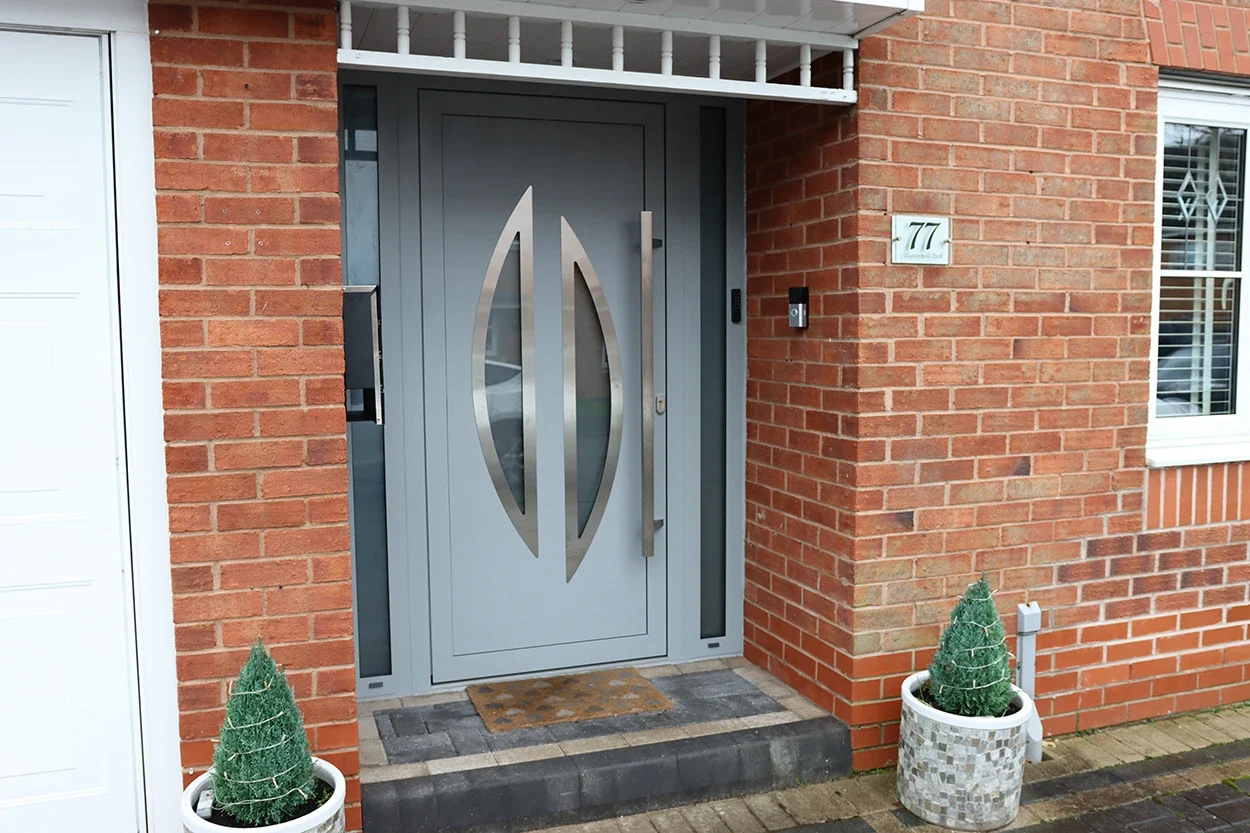 Grey aluminium entrance door installed in a brick house