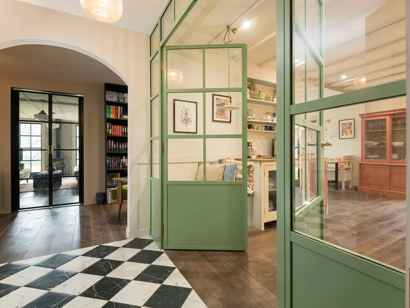 Pale green internal aluminium doors between a tiled hallway and kitchen