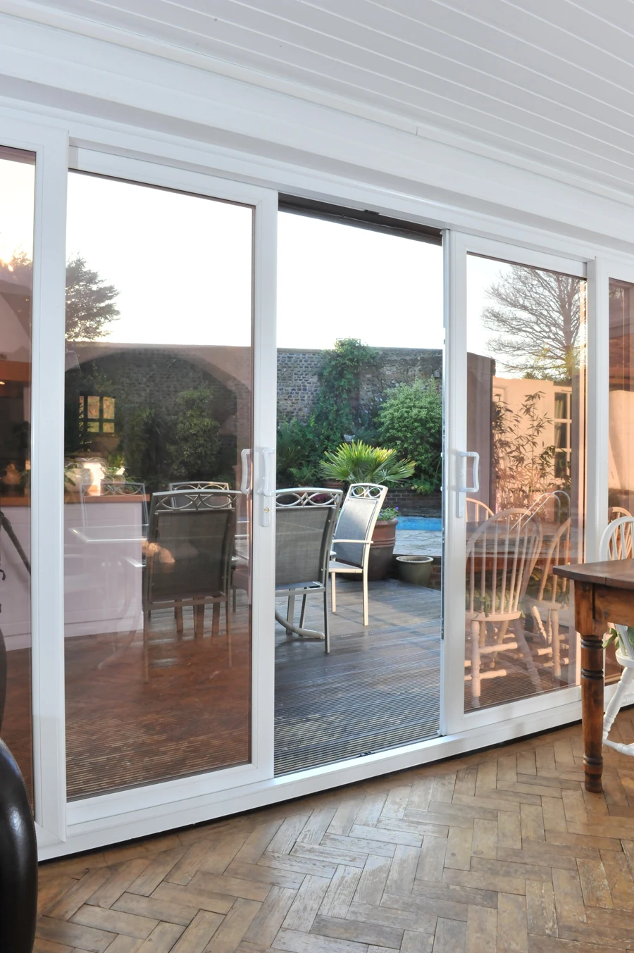 White uPVC sliding patio door opening from a dining room onto decking