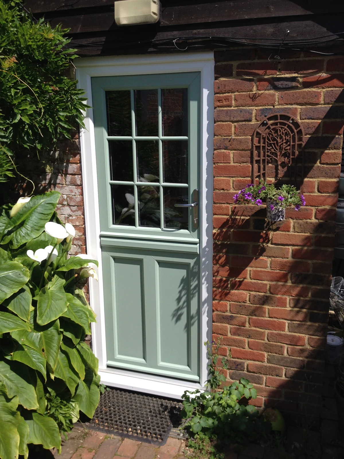Green uPVC stable door in a traditional brick cottage entrance